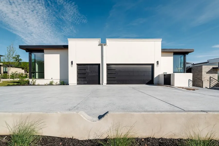Two dark flush panel garage doors on a contemporary white house
